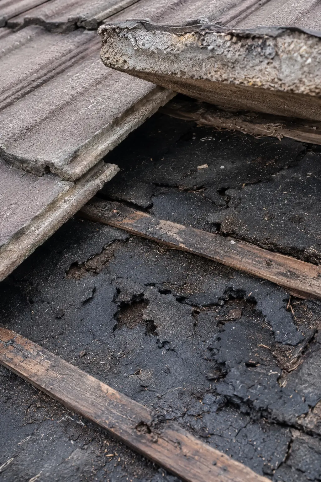Old bitumen felt gone brittle and torn beneath the tiles on a Dublin roof