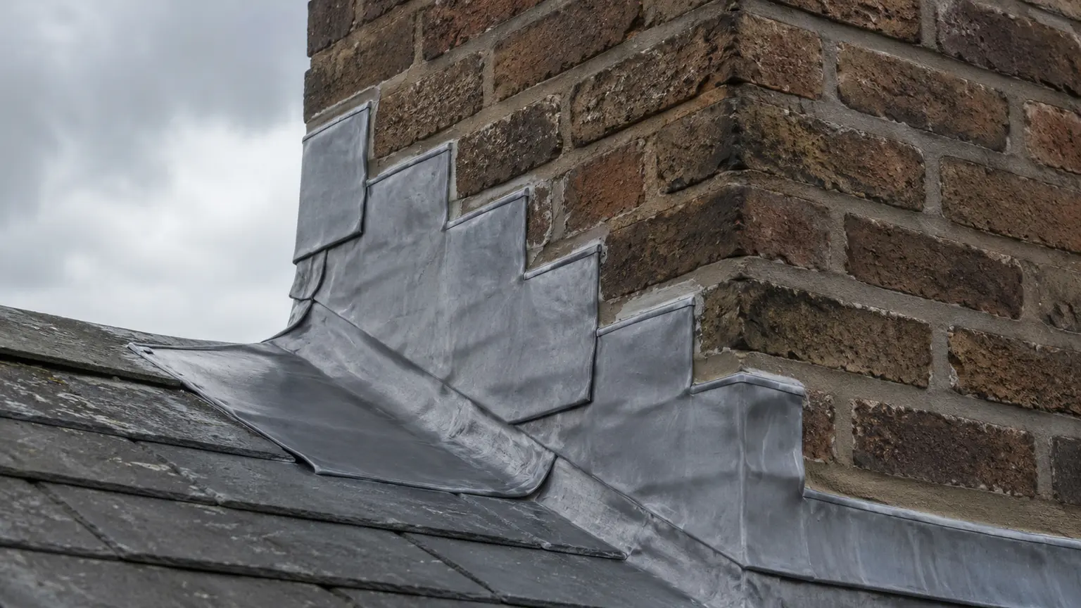 Close view of new flashing where a chimney meets the slates