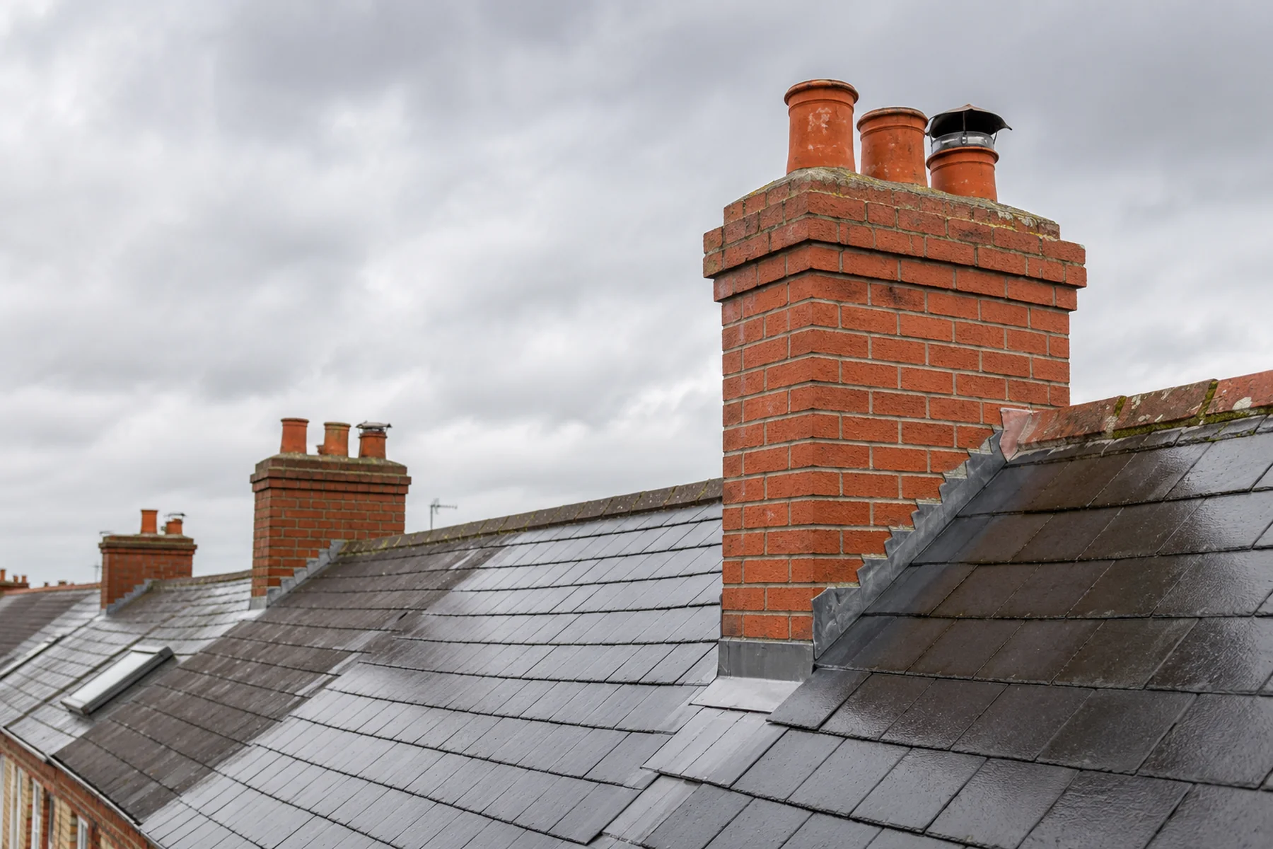 A restored brick chimney stack with fresh lead flashing on a Dublin roof