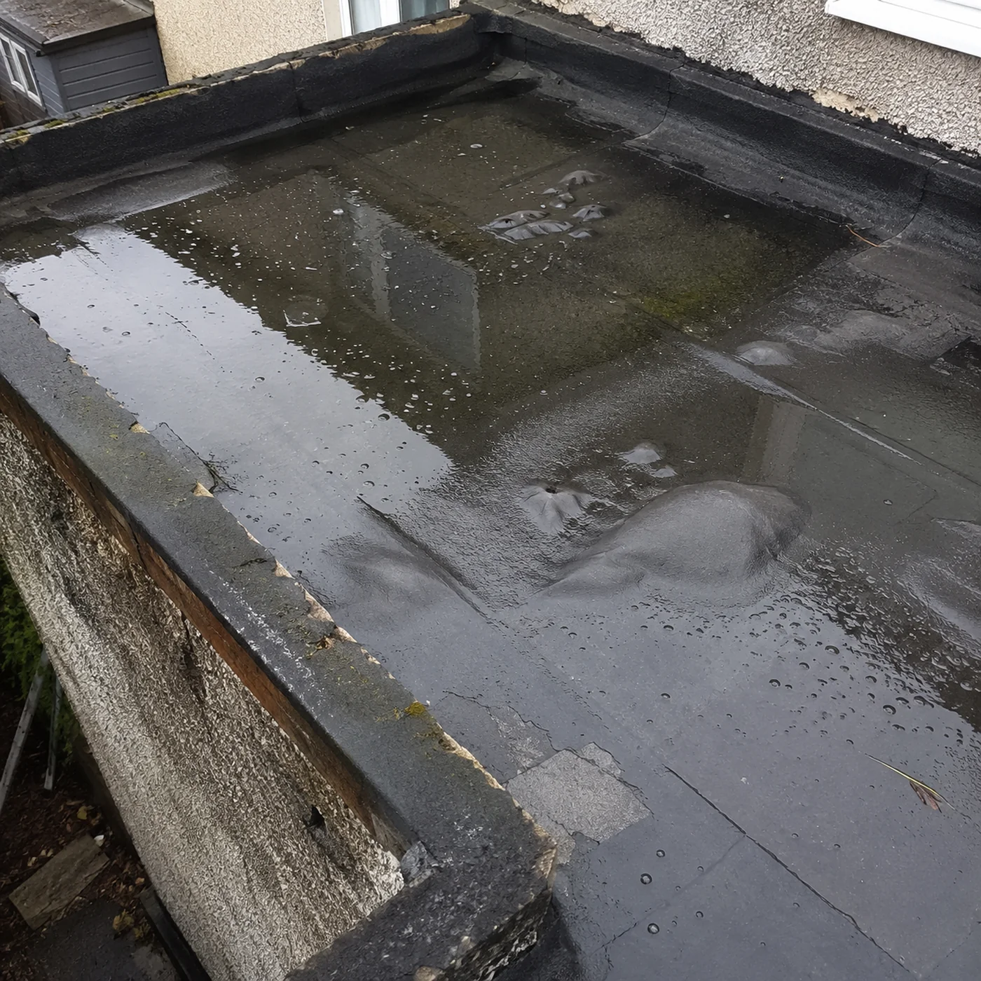 Ponding water on a worn Dublin flat roof in need of repair