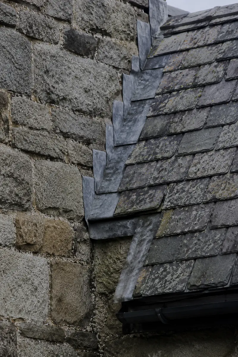 A granite wall meeting slate roof and stepped lead flashing on a Blackrock villa
