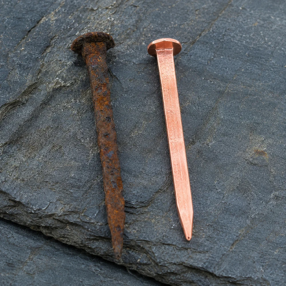 A rusted Victorian iron roof nail beside a new copper nail