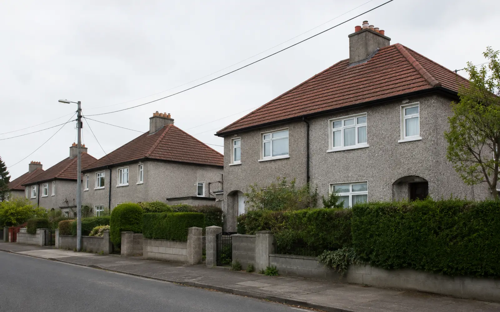Pebbledash 1940s Dublin semis with hipped clay tile roofs