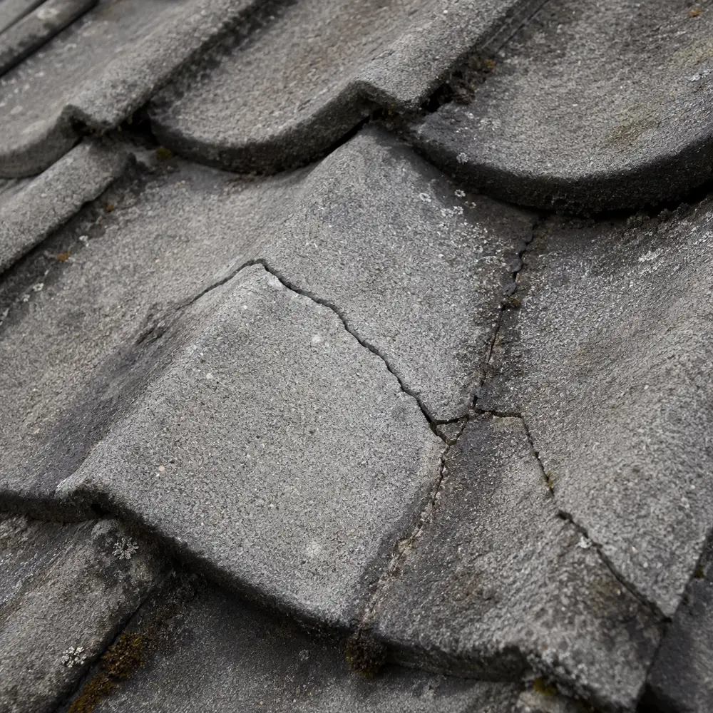 A concrete roof tile split by frost damage on a Dublin roof